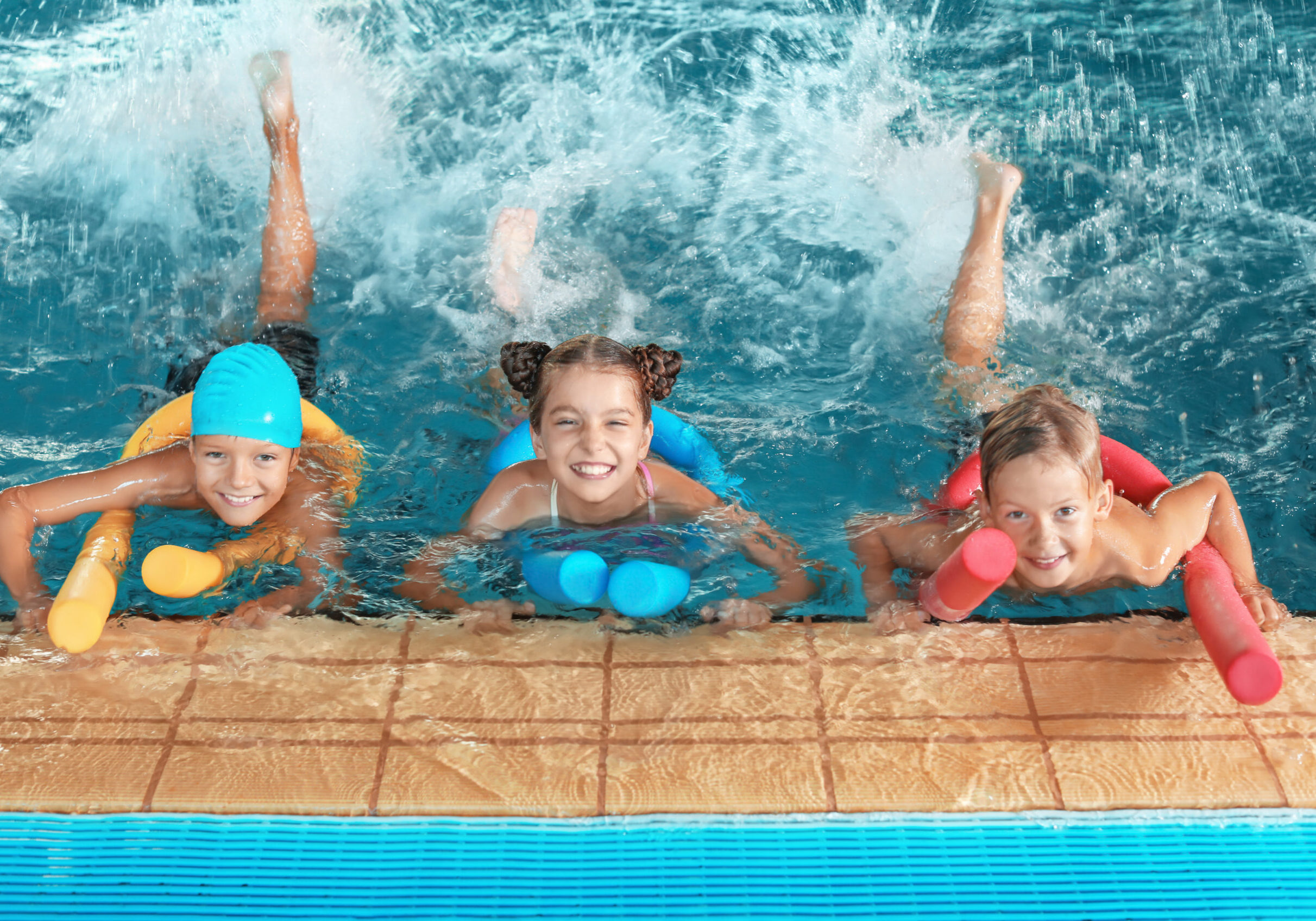 Little,Kids,With,Swimming,Noodles,In,Indoor,Pool